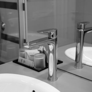 Stylish stainless steel faucet in black and white with mirror reflection in a modern bathroom.